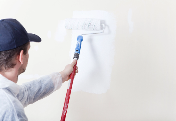 Die Wand wird von einem Maler in der Farbe weiss gestrichen